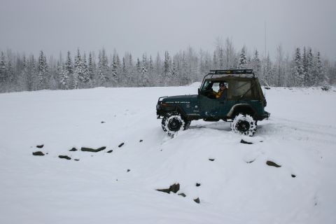 2003 Jeep TJ - A green Jeep Wrangler navigates a snowy landscape with a forest in the background.