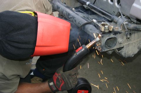 2003 Jeep TJ - Welding is being done on the vehicle's frame, with sparks flying from the metalwork.