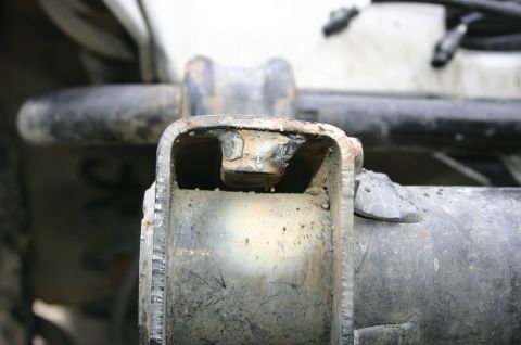 2003 Jeep TJ - A close-up view of a damaged and repaired metal bracket on a vehicle's frame.