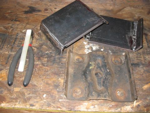 1995 Ford Bronco - Metal brackets and rusty plate on a wooden surface, with pliers and a white stick.