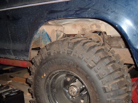 1979 Ford Bronco - Off-road tire and suspension detail on a dark blue vehicle, with 'SWAMPER' visible on the tire sidewall.
