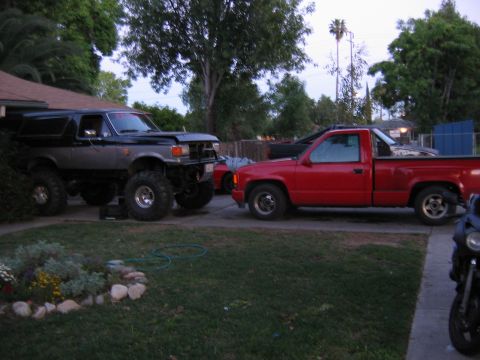 1987 Ford Bronco - A modified Ford Bronco and a red pickup truck are parked in a driveway.