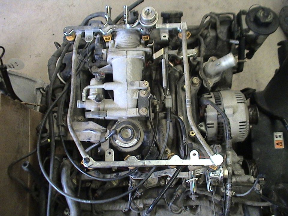 Top view of removed V-engine showing upper intake, fuel rail, alternator and accessory pulleys