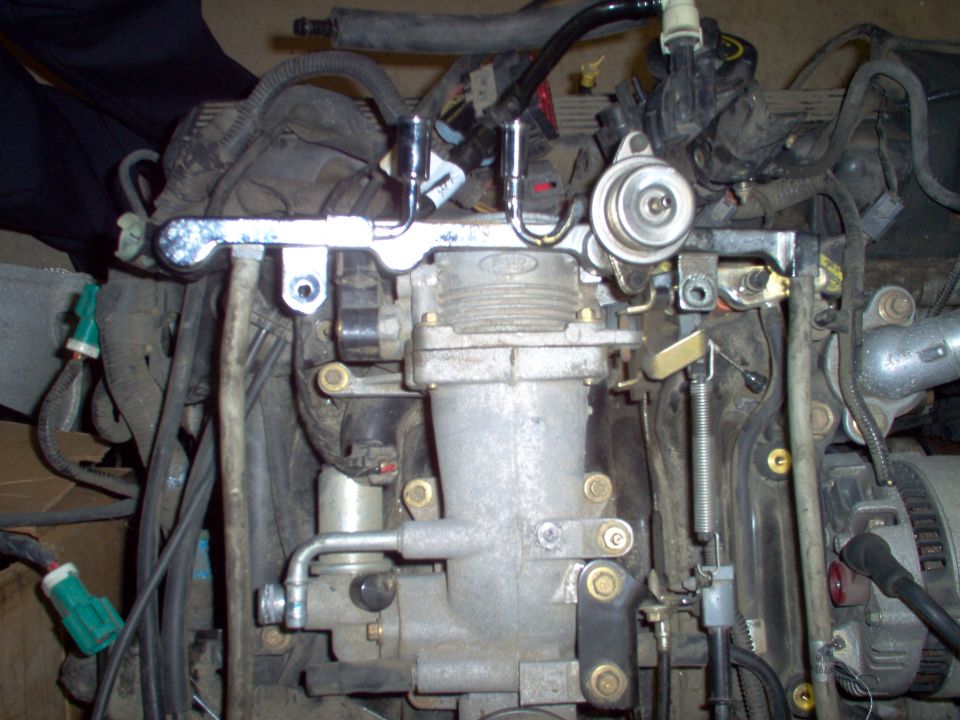 Front of a removed Ford engine with upper intake, fuel rails, pressure regulator and wiring harness