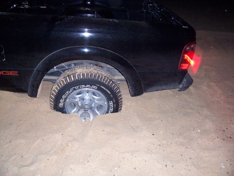 2003 Ford Ranger - Truck stuck in sand, rear wheel buried. The word 'DODGE' is visible on the side.