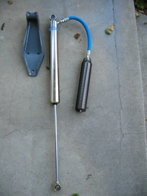 1992 Ford Bronco - A shock absorber assembly and mounting bracket are laid out on a concrete surface.