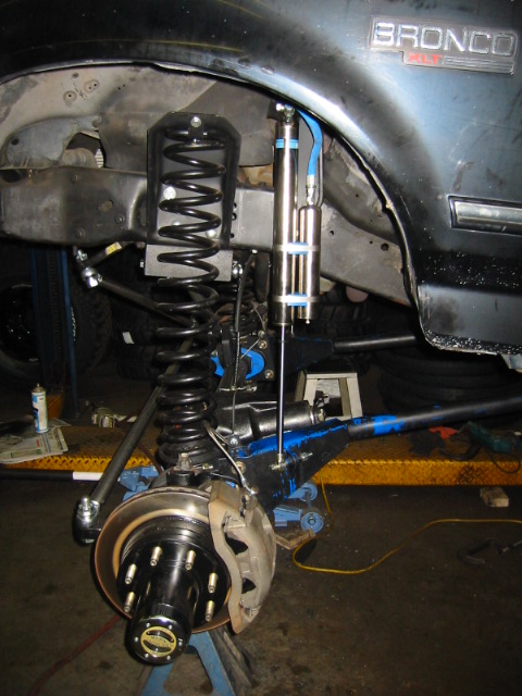 1992 Ford Bronco - Close-up of a modified Ford Bronco's front suspension system, showing new shocks and heavy-duty springs.