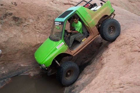 1990 Ford Bronco - Modified green SUV tackles a challenging rocky trail with a driver at the wheel.