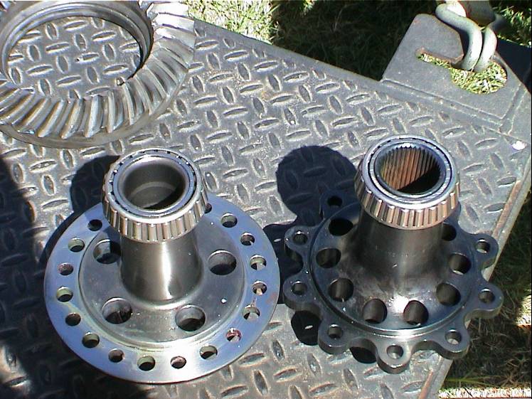 Differential gears and bearings on a diamond plate surface. One gear is larger and silver, the other is smaller and black