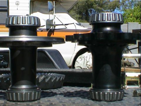 1979 Ford Bronco - Close-up of two differential bearing and race sets with a covered vehicle and trailer in the background.