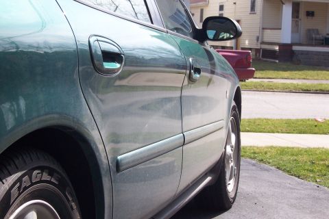 2000 Ford Taurus - Side profile of a green 2000 Ford Taurus, showing its door handles and a portion of the tire.