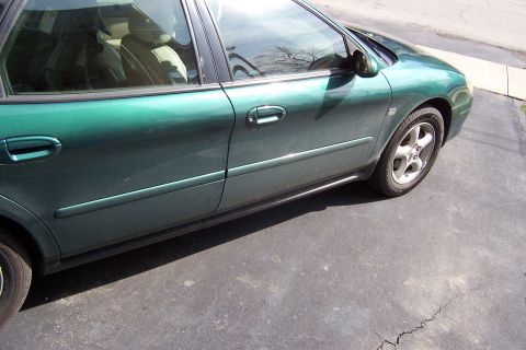 2000 Ford Taurus - Side profile of a green 2000 Ford Taurus sedan parked on asphalt.