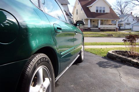 2000 Ford Taurus - The side of a green sedan is shown parked in a driveway with houses in the background.