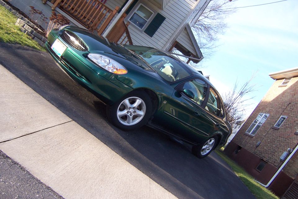 Green 2000 Ford Taurus sedan parked on a driveway, front 3/4 view