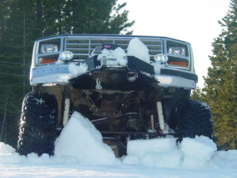1986 Ford Bronco - This lifted Ford Bronco is equipped with a winch and plow, partially buried in snow.