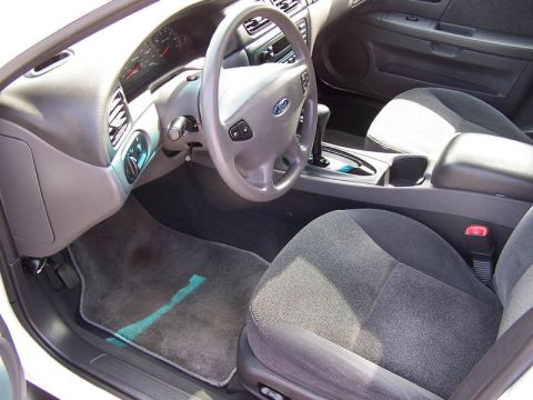 2001 Ford Taurus - The interior of a 2001 Ford Taurus, cloth seats, a gray dashboard, and a center console with a gear shifter.