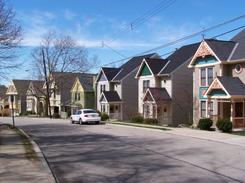 2001 Ford Taurus - A white sedan is parked on a street lined with colorful houses under a blue sky.