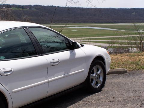 2001 Ford Taurus - A white sedan is parked outdoors with a scenic view of a body of water and distant hills.