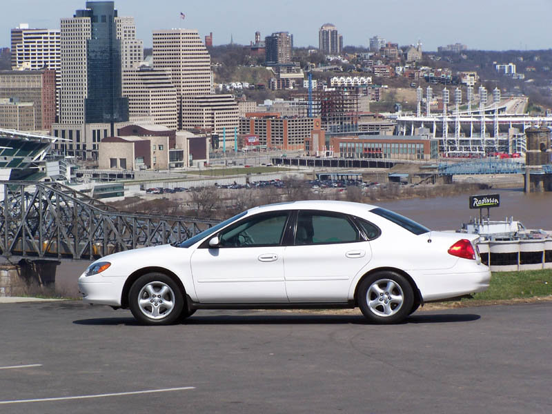 2001 Ford Taurus sedan, side view, parked with city skyline behind it