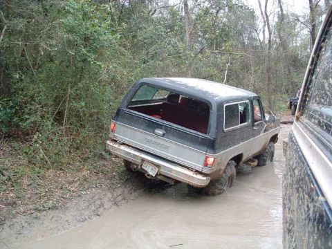 1993 Ford Bronco - A Chevrolet K5 Blazer navigates a muddy trail, with another vehicle partially visible on the right.