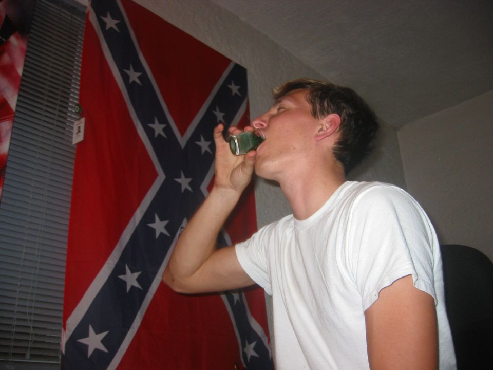 Man drinking from a can, Confederate flag in background