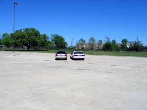 2000 Ford Crown Victoria - Two Ford Crown Victorias are seen from the rear, parked in an open lot under a clear blue sky.
