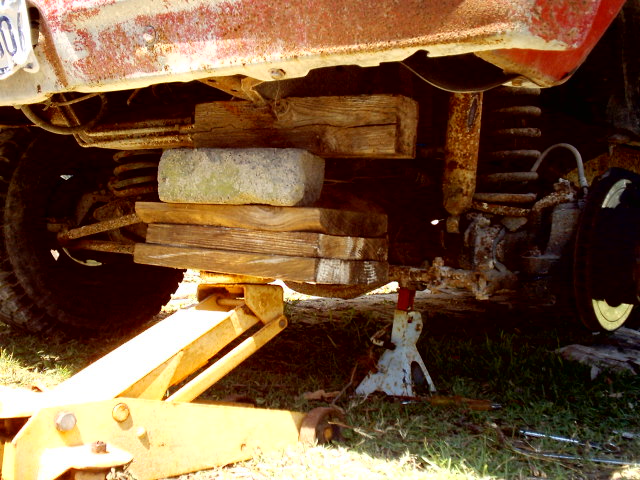 Undercarriage of vehicle on blocks and jacks, showing suspension and frame