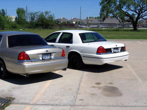 2000 Ford Crown Victoria - Two Ford Crown Victorias are parked in a lot, viewed from the rear.