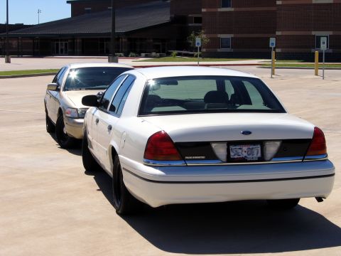2000 Ford Crown Victoria - Two white Ford Crown Victorias are parked in a lot, with the rear of one vehicle prominently displayed.