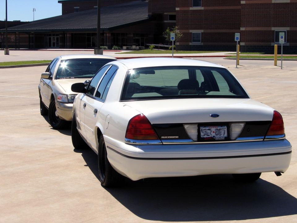 Rear view of two white Ford Crown Victorias, one in foreground