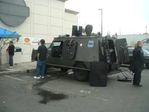 1999 Ford Crown Victoria - An armored vehicle, possibly for law enforcement, is parked with its doors open in a parking lot.