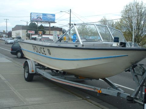 1999 Ford Crown Victoria - A police boat is seen on a trailer parked on the side of the road.