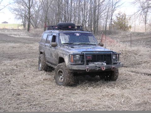 1995 Jeep Cherokee - Mud-covered 1995 Jeep Cherokee equipped for off-road use with a roof rack and winch.