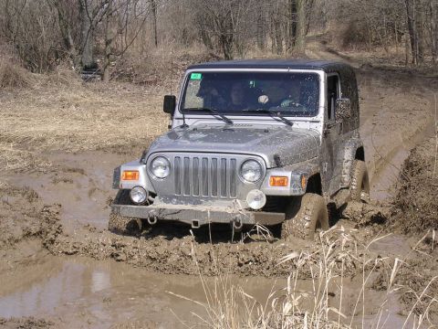 1995 Jeep Cherokee - Silver Jeep Wrangler TJ model stuck in mud on an off-road trail.