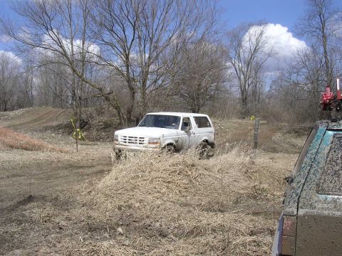 1995 Jeep Cherokee - A white Ford Bronco navigates a muddy off-road course with another vehicle visible in the foreground.