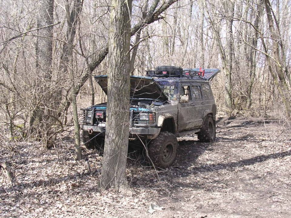 1995 Jeep Cherokee with hood open, parked in woods