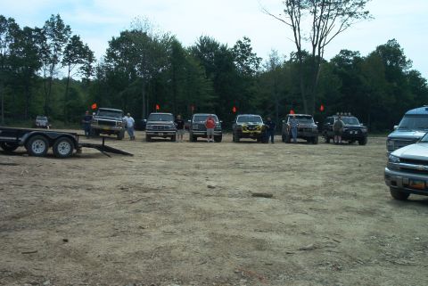 1993 Ford Bronco - Several off-road vehicles, including a 1993 Ford Bronco, are gathered in a dirt lot with a trailer.