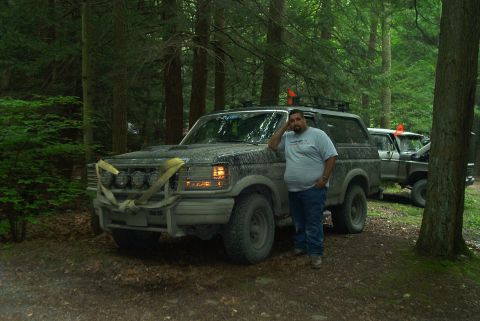 1993 Ford Bronco - A man stands next to a muddy 1992 Ford Bronco in a wooded area, with another vehicle visible behind it.