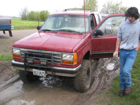 1991 Ford Explorer - Red 1991 Ford Explorer is stuck in the mud with its driver door open.