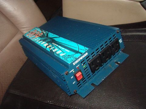 1993 Ford Bronco - A blue StatPower 3000 power inverter is placed on dark car upholstery.