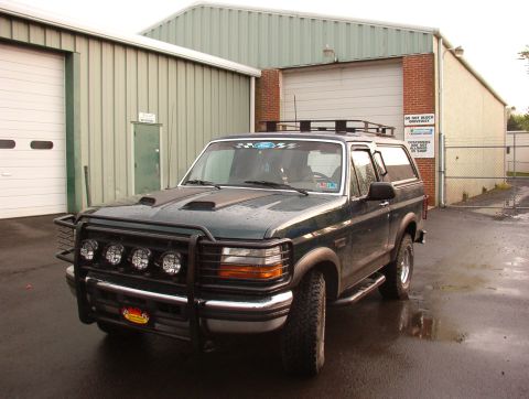 1993 Ford Bronco - This 1993 Ford Bronco features a custom bull bar and hood scoops, parked in front of a commercial building.