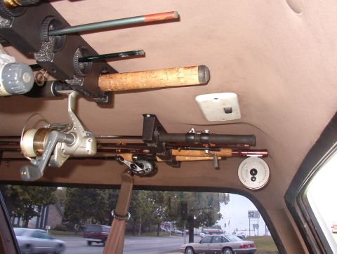 1993 Ford Bronco - Fishing rods and reels are stored overhead inside a vehicle, with a street scene visible through the rear window.