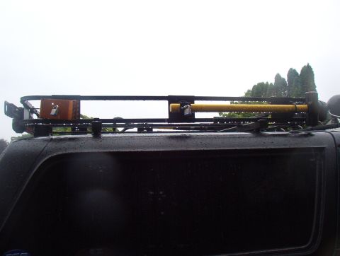 1993 Ford Bronco - A black SUV is equipped with a roof rack holding a sledgehammer and a wooden box.