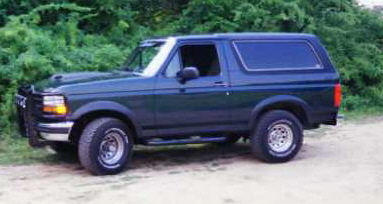 1993 Ford Bronco - 1993 Ford Bronco in dark green, seen from the front three-quarter angle.