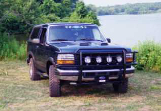 1993 Ford Bronco - This Ford Bronco is parked outdoors near a lake, with lush greenery surrounding it.