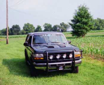 1993 Ford Bronco - A Ford Bronco sits in a field under a clear sky, with a cornfield to its right.