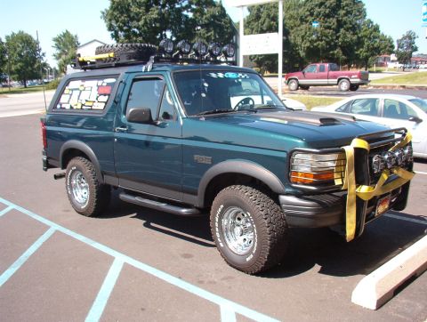 1993 Ford Bronco - This modified Ford Bronco is parked in a lot, with other vehicles visible in the background.