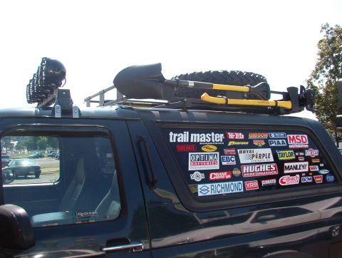 1993 Ford Bronco - This SUV is heavily customized with numerous aftermarket stickers adorning its side window and a roof rack equipped for off-road adventures.
