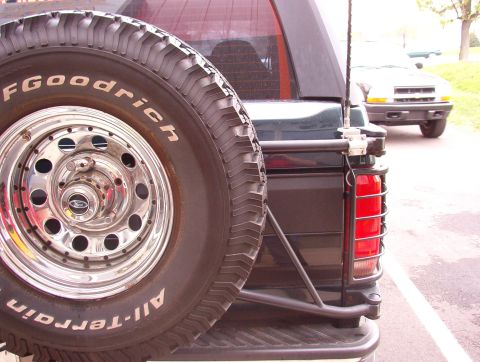 1993 Ford Bronco - Rear view of a 1993 Ford Bronco showing its spare tire and a second vehicle behind it.