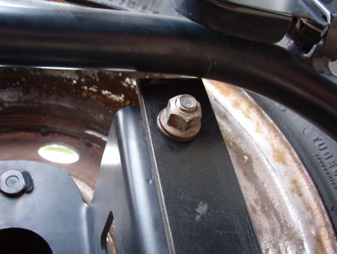 1993 Ford Bronco - Close-up view of a metal bracket attached to a wheel rim, with a black tube overhead.